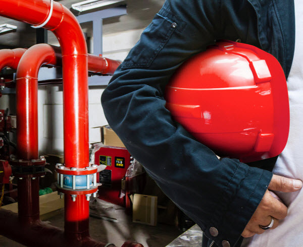 Engineer holding red helmet in the fire protection system room