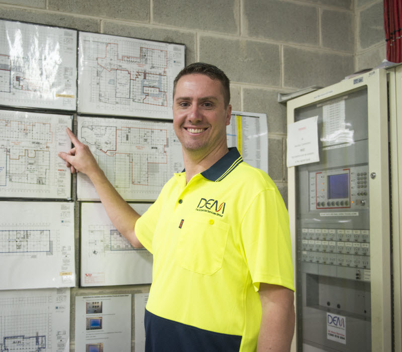 Fire expert looking at the camera while pointing at the Fire exit building plan
